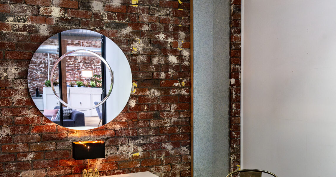 The Looking Glass meeting room at ko&co workhub with exposed brick, round table, and signature mirror. South Melbourne meeting rooms and coworking space for small business