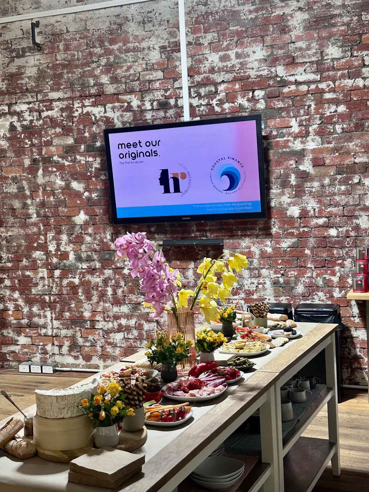 ko&co workhub launch grazing table with The Originals logos—Head Recruitment and Coastal Finance—displayed on screen