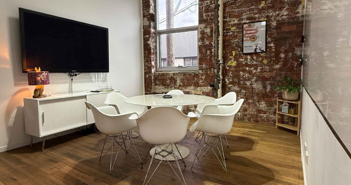 The Leap meeting room with a round table, chairs, and presentation screen at ko&co workhub in South Melbourne. Meeting room hire in South Melbourne
